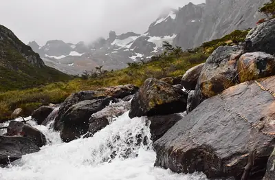 a mountain stream under snow peaks