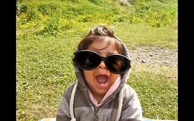 a small girl in sunglasses far too big for her