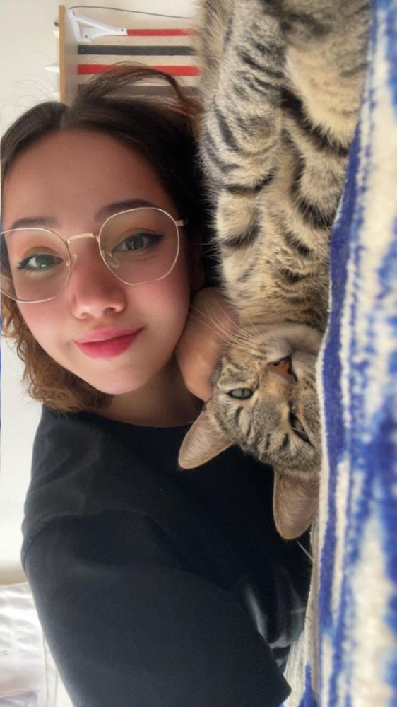 Erica lying down with her tabby cat draped upside down over her shoulder