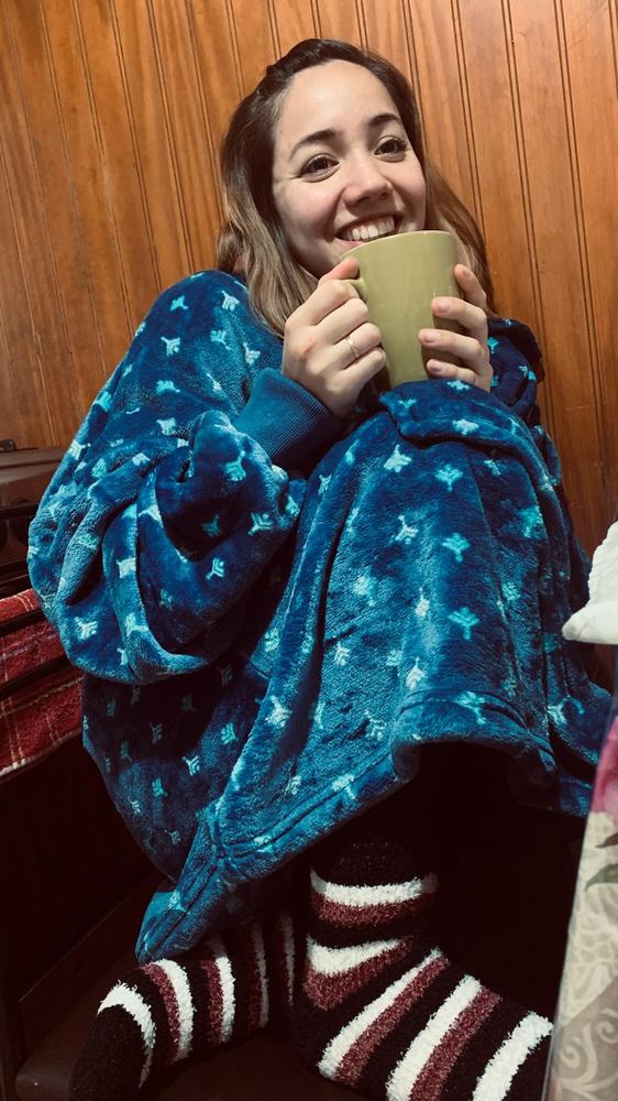 Erica wrapped in a fleece blanket and striped socks, holding a mug with both hands