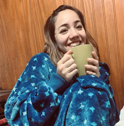 Erica wrapped in a star-print fleece blanket, holding a mug with both hands