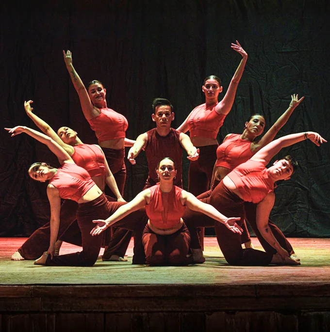 Erica on stage with her dance company in red, mid-pose